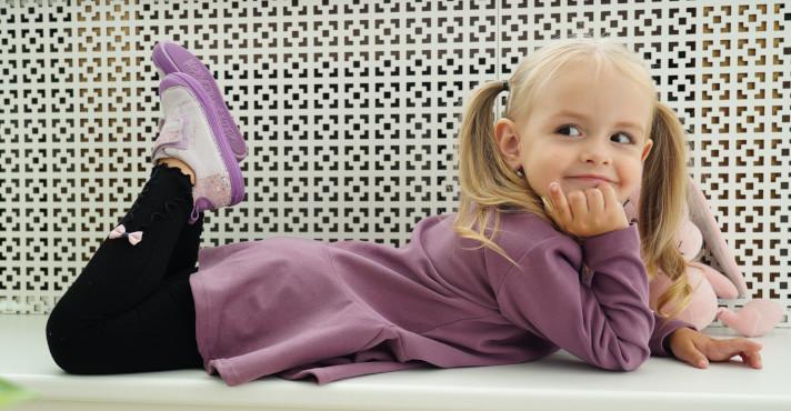 cute little girl with stuffed toy smiling while showing off her new pair of shoes