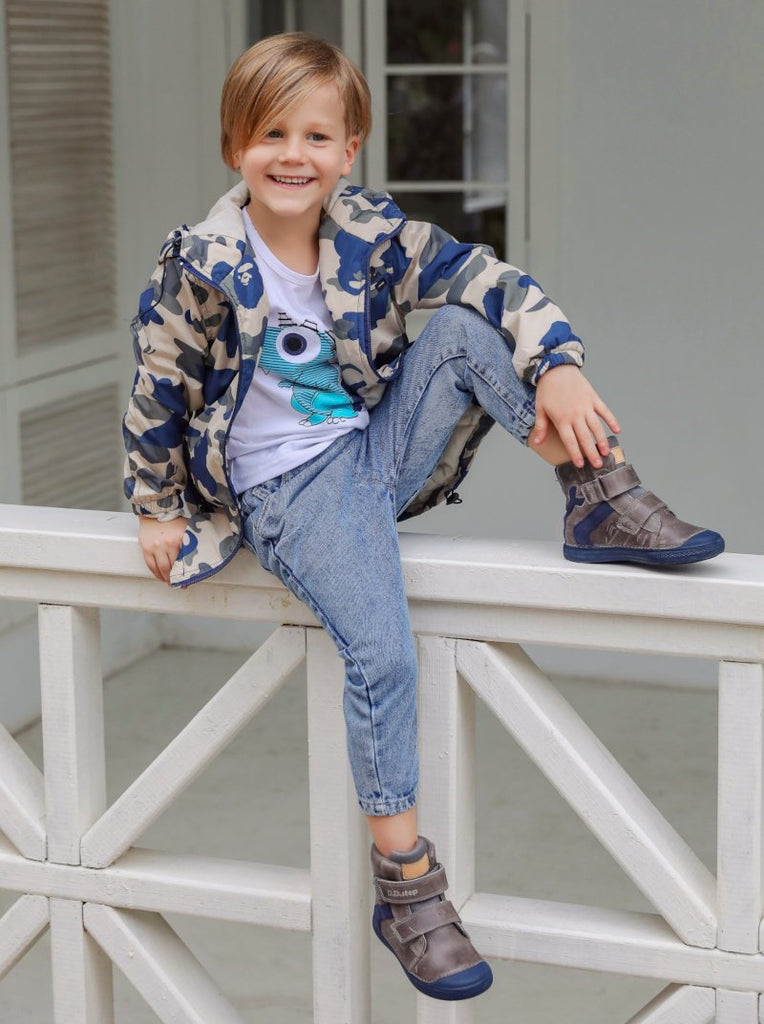 a boy sitting on the railing of a porch, wearing his new brown D.D. Step boots