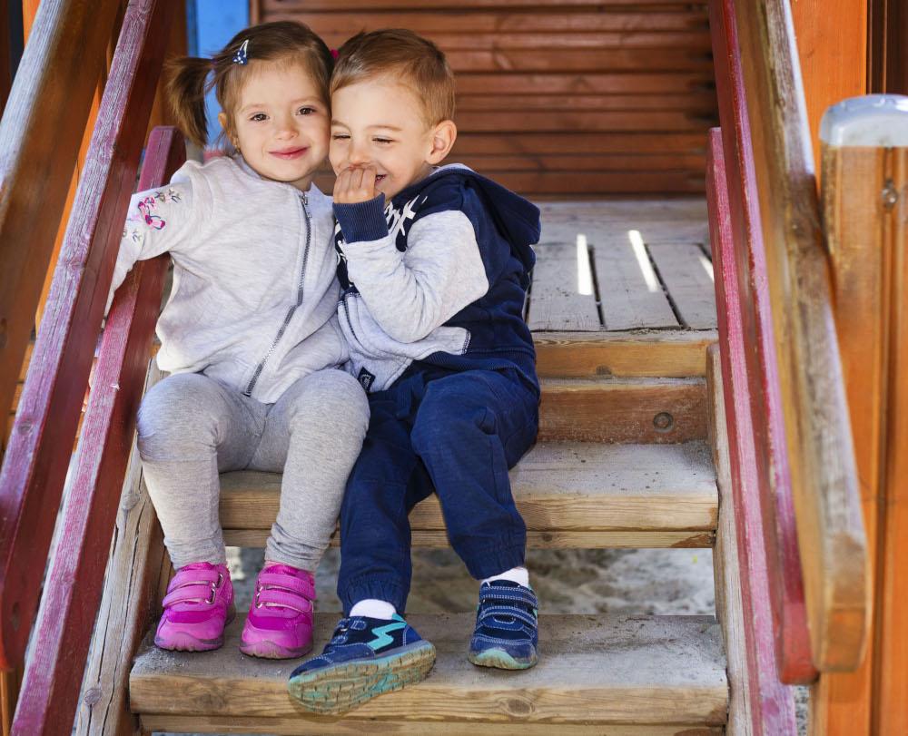 image of a toddler boy and girl at a playground talking to each other